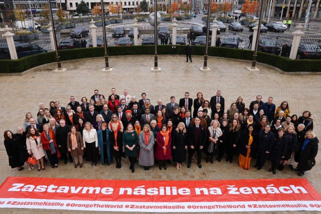 ngo-illustration-Artboard 5 Skupina aktivistov a aktivistiek, v popredí prezidentka Zuzana Čaputová. Pri nohách majú baner s nápisom Zastavme násilie na ženách.